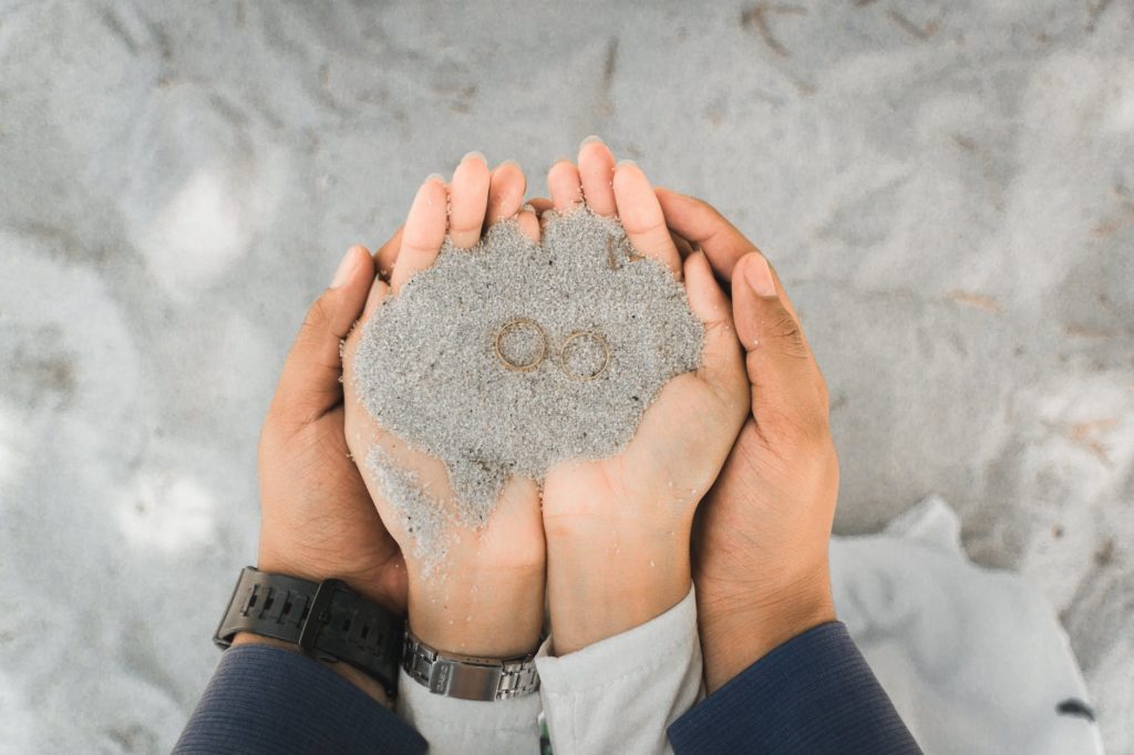 two person s hands holding a sand